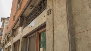 Fachada de edificio con un ventanal grande, una reja metálica y un letrero con el número '52'.
