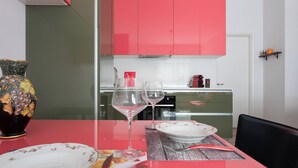 Una cocina moderna con armarios rojos, una mesa de comedor con un florero, platos y una copa de vino.