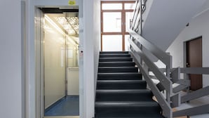 Una escalera moderna con barandilla de metal que lleva a un ascensor.