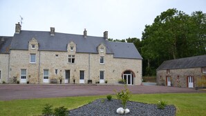 A stone building with a large driveway and a landscaped garden area with rocks and small plants. - 2-person cocoon gîte in the heart of nature, very bright, 15 minutes from UTAH BEACH (Picauville)