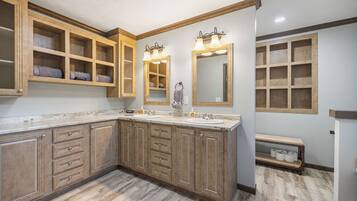 A bathroom with wooden cabinetry, two sinks, and a large mirror.