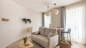 Una sala de estar moderna con un sofá, una mesita, una silla y una cesta.