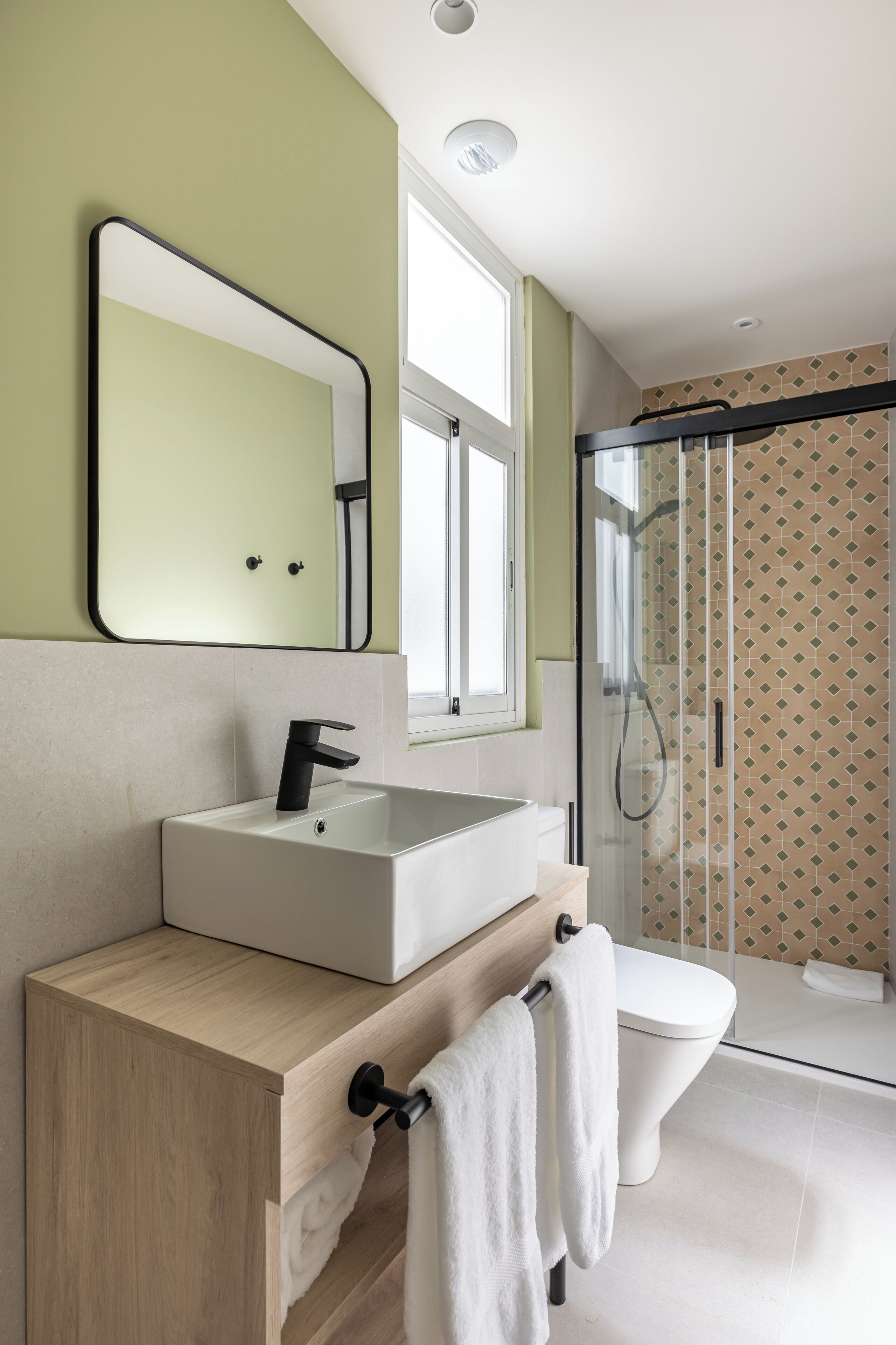 Un baño moderno con un lavamanos blanco, un espejo y una cabina de ducha de vidrio.