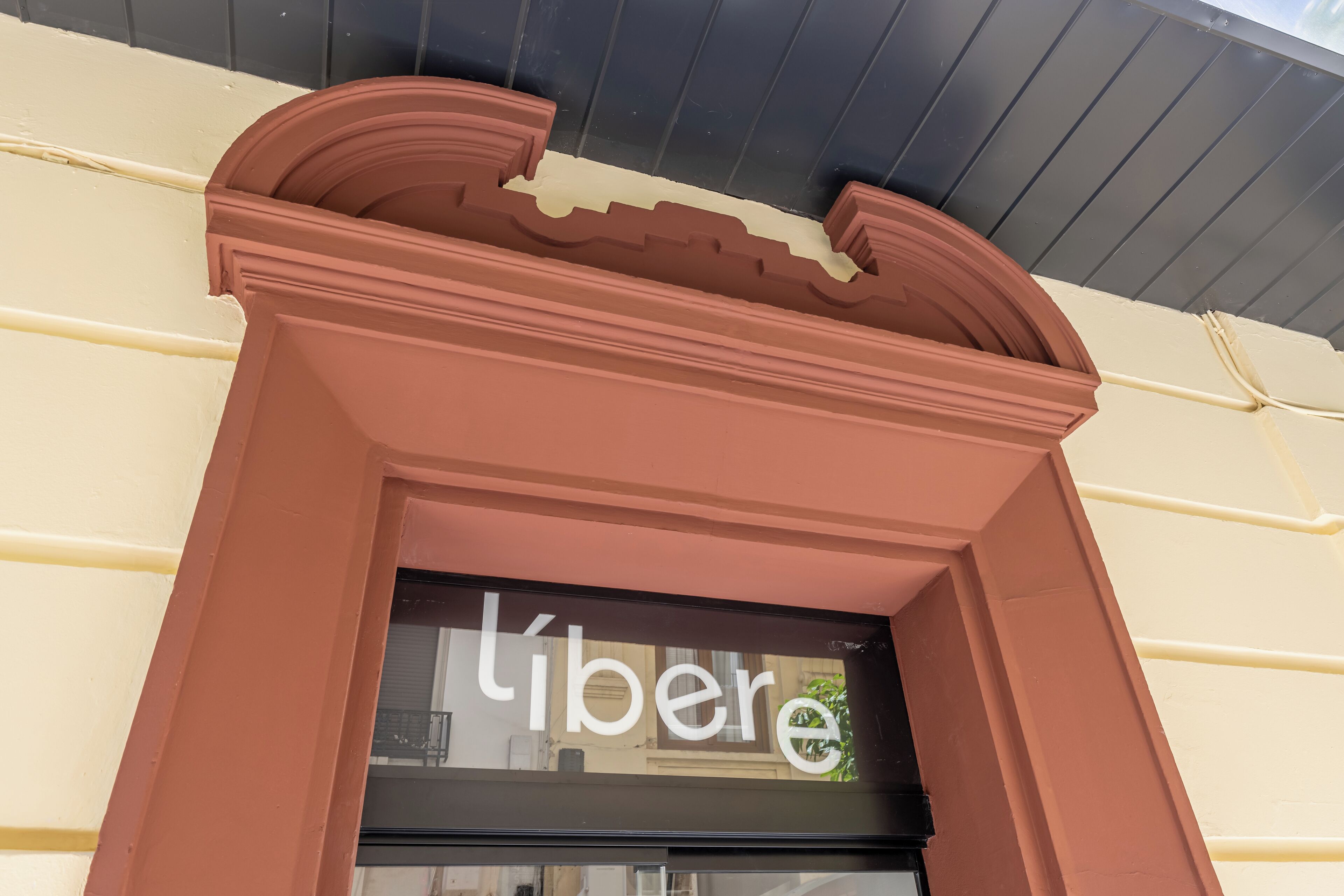 Ein Schaufenster mit einer braunen Fassade und einem schwarzen Fenster, auf dem das Wort "liber" zu sehen ist.