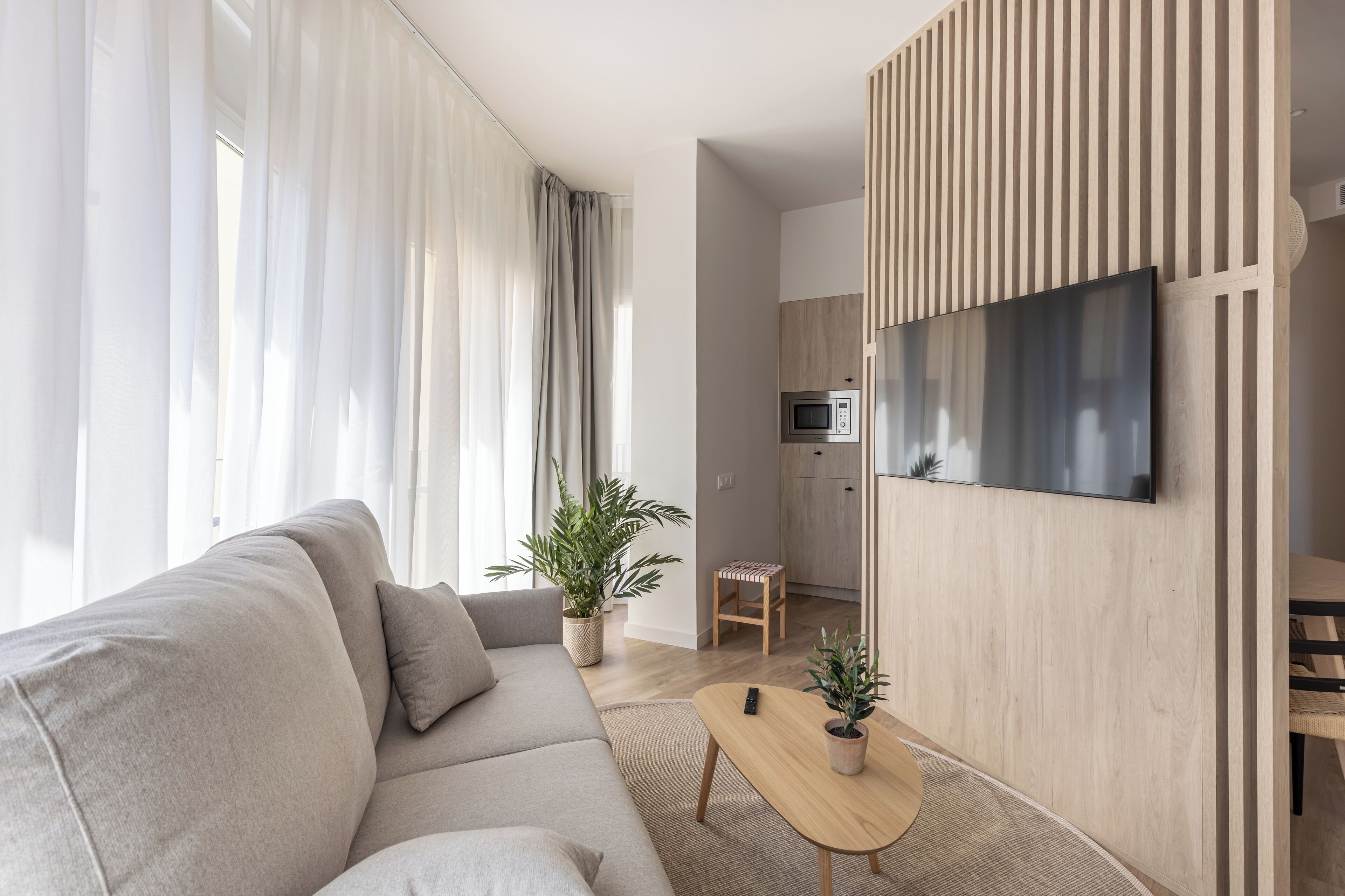 Un salon moderne avec un canapé, une table basse et un téléviseur fixé à un mur en bois.
