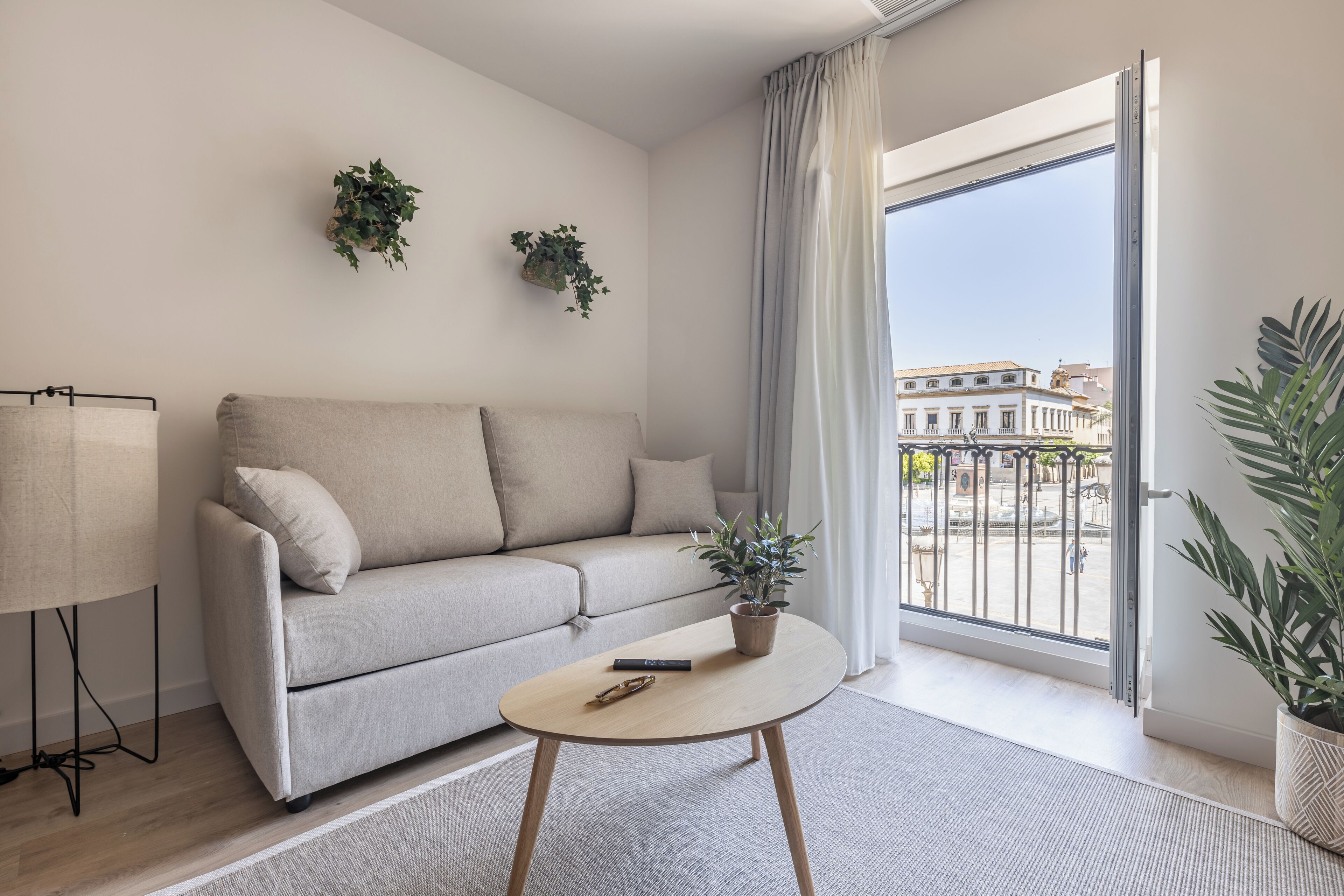 A modern living room with a sofa, a coffee table, and two potted plants.