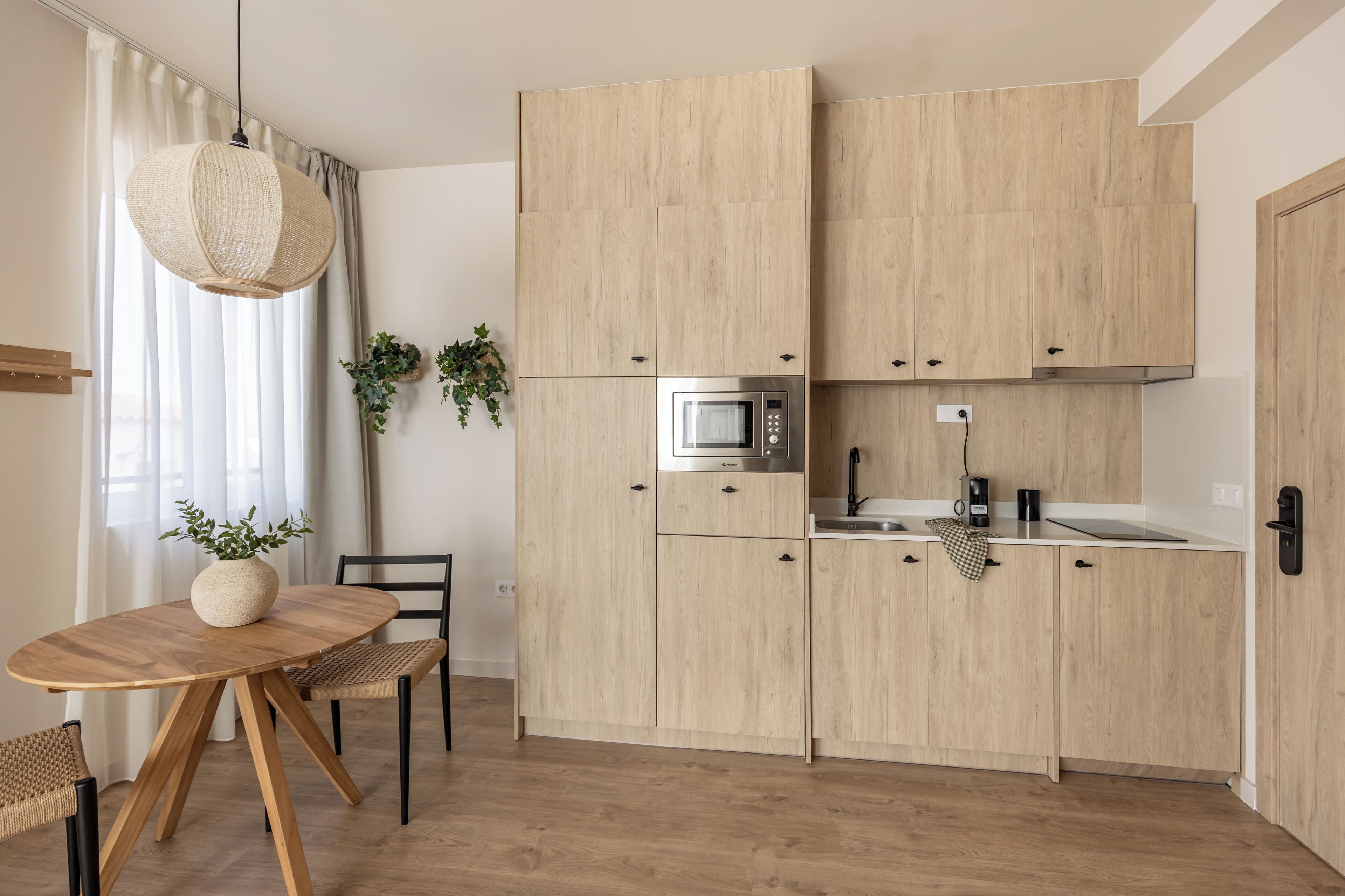 Une cuisine moderne avec des meubles en bois, un four à micro-ondes encastré et un coin repas comprenant une table ronde et des chaises.