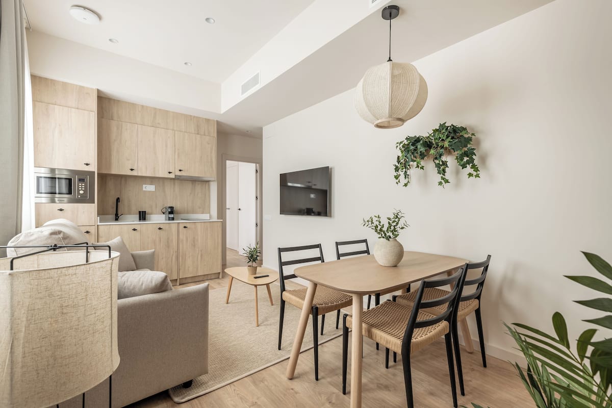 Une cuisine moderne avec des meubles en bois, un four à micro-ondes encastré et un coin repas comprenant une table et des chaises en bois.