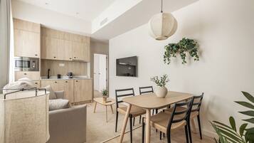 Una cocina moderna con armarios de madera, microondas integrado y un comedor con mesa y sillas de madera.
