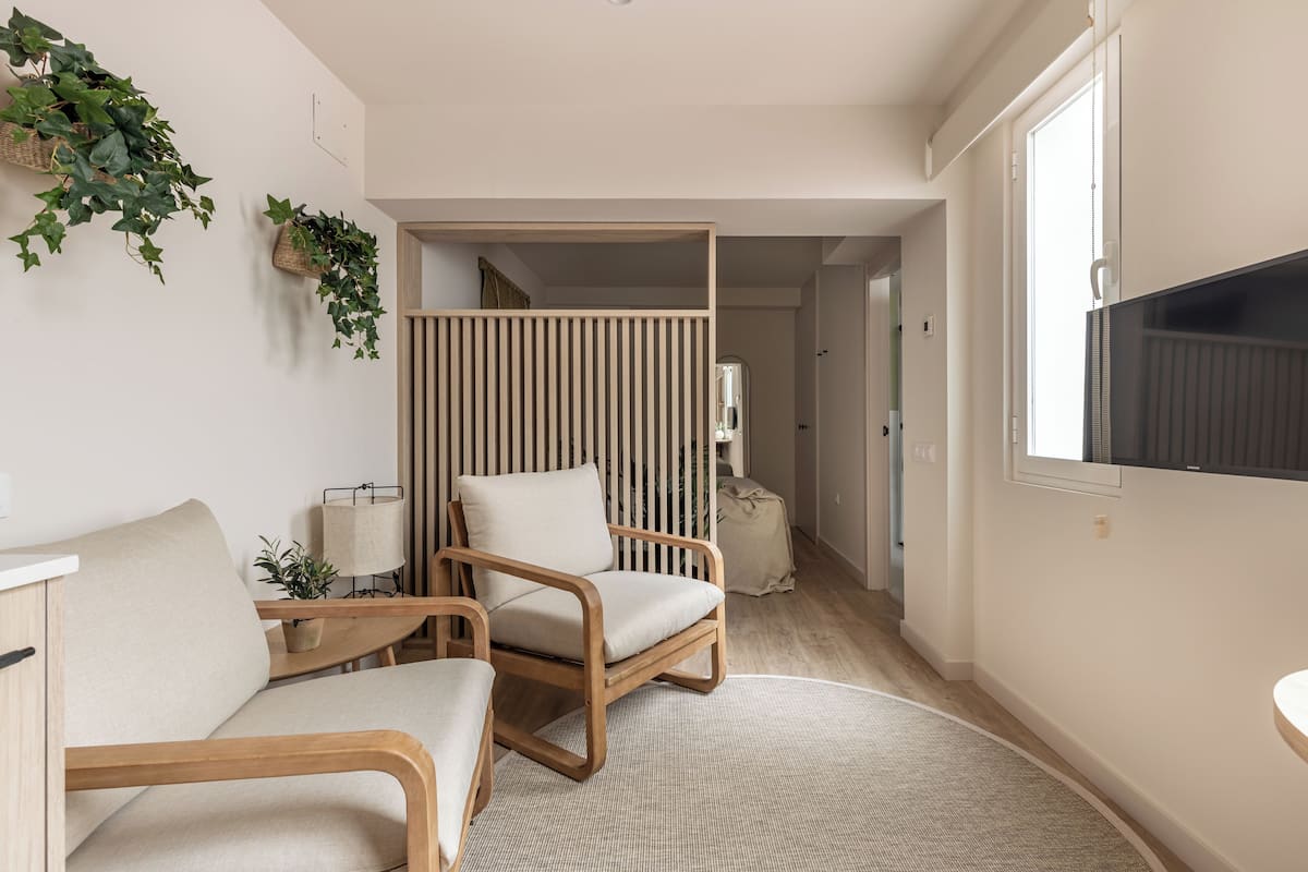 Un intérieur moderne avec une chaise en bois, un canapé et une grande fenêtre.