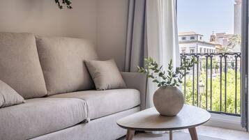 Een moderne woonkamer met een beige bank, een ronde houten salontafel en een potplant.