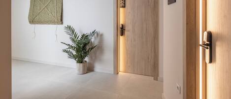 A hallway with a wooden door labeled "302", a potted plant, and a wall-mounted sign with a symbol.