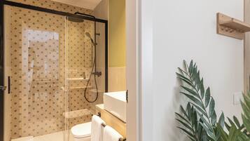 A modern bathroom with a glass-enclosed shower, a toilet, and a sink.