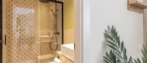 A modern bathroom with a glass-enclosed shower, a toilet, and a sink.