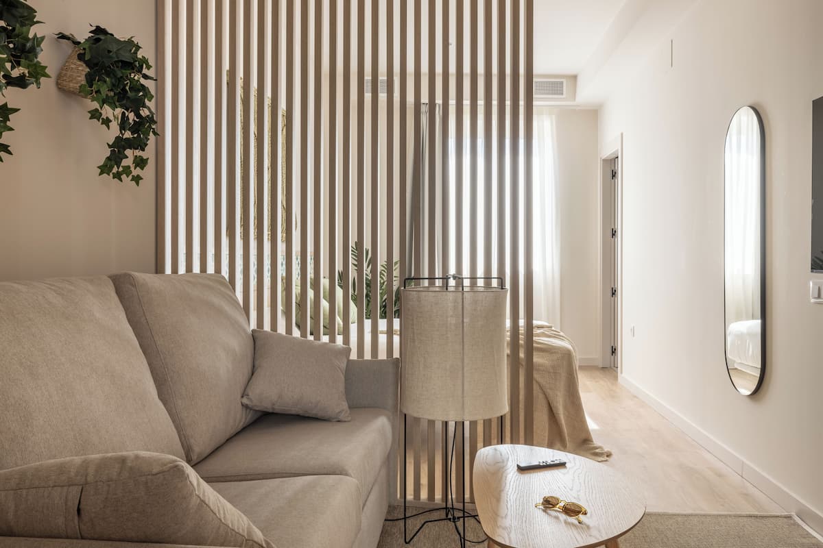 Un salon moderne avec un canapé, une lampe, une petite table et un miroir.