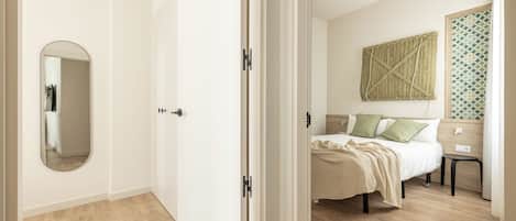 A bedroom with a bed, bedside tables, a mirror, and a wall-mounted artwork.