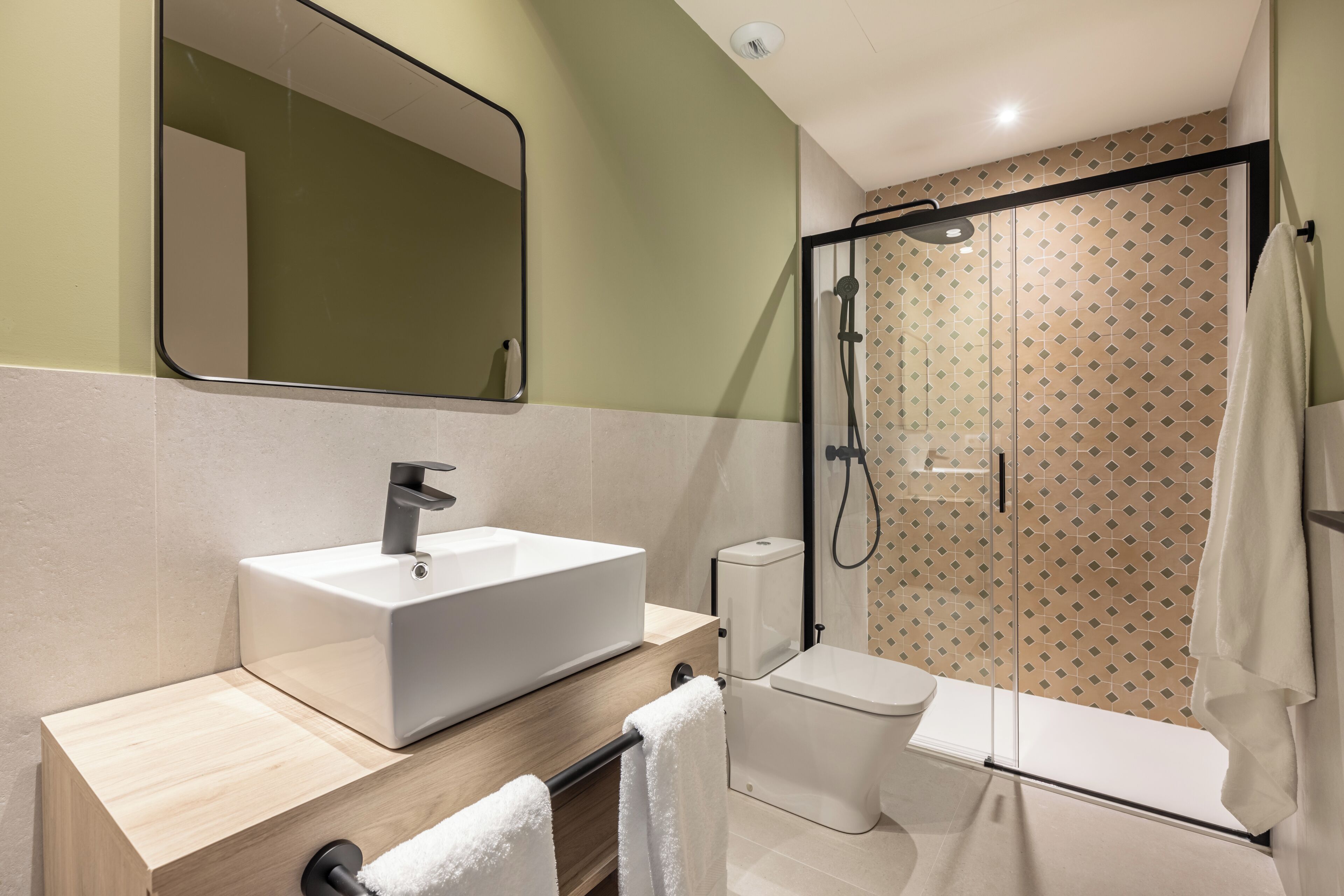 Een moderne badkamer met een groot wastafel, toilet en een douchecabine met glazen wanden.