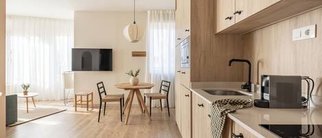 Una cocina moderna con armarios de madera, un comedor con una mesa redonda y sillas, y un horno empotrado.