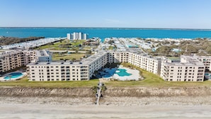 A beachfront hotel with multiple buildings, a central pool, and a beach in the foreground. - Summer Winds 436B- 2BR Condo w/ Ocean Views & Pools! (Indian Beach)