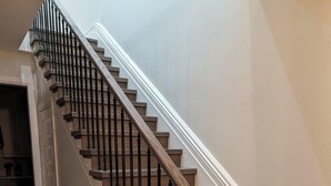 A wooden staircase with black balusters and a handrail, leading to a landing.