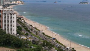 Un paysage urbain côtier avec une plage, des immeubles de grande hauteur et une vue dégagée sur l’océan.