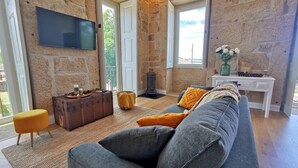 A cozy living room with a stone wall, a sofa, a television, and a small table with a 'Welcome' sign. - Solar dos Condes da Azenha (Sernancelhe)