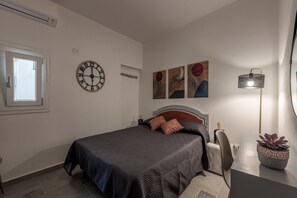 A bedroom with a bed, a wall clock, artwork, a lamp, and a potted plant. - Casa delle Travi by Wonderful Italy (Palermo)