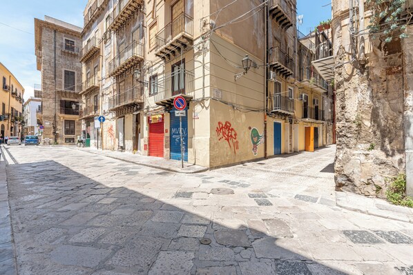 A narrow cobblestone street with historic buildings, a no parking sign, and a closed shop with a red door. - Casa delle Travi by Wonderful Italy (Palermo)