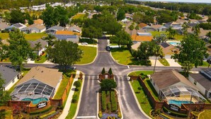 An aerial view of a residential area with houses, a central road, and a gated entrance. - Private Pool • Game Room • Near Disney (Davenport)