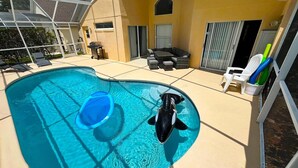 A swimming pool with a slide, lounge chairs, and a covered patio area. - Private Pool • Game Room • Near Disney (Davenport)