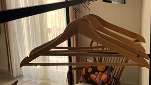 Une pièce comprenant une chaise en bois, un porte-manteau en bois et un téléviseur fixé au mur.