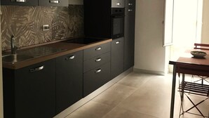 Une cuisine moderne avec des meubles de couleur sombre, un évier en acier inoxydable et un four encastré.
