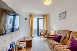 A living room with a sofa, ottoman, chair, and a flat-screen TV. - 3 Bed in Ilfracombe (oc-s29585) (Ilfracombe)