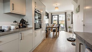 A modern kitchen with a dining area, built-in appliances, and a view to the outside. - 3 Bed in Ilfracombe (oc-s29585) (Ilfracombe)