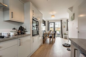 A modern kitchen with a dining area, built-in appliances, and a view to the outside. - 3 Bed in Ilfracombe (oc-s29585) (Ilfracombe)