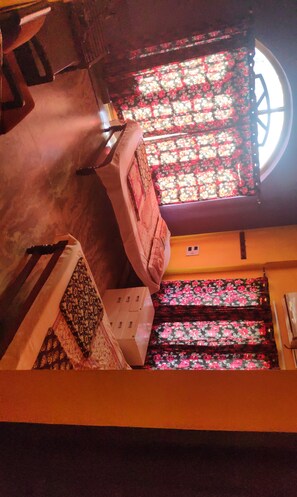 A staircase with floral-patterned curtains and a window with a circular design. - Hotel Sri Devi Comforts (Mudigere)
