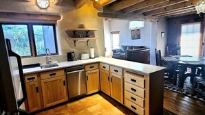 Eine Küche mit Holzschränken, einem Geschirrspüler und einem Essbereich mit Tisch und Stühlen.