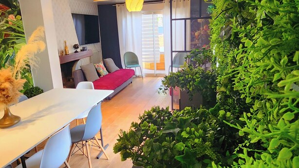 A modern living room with a dining area, a sofa, and a large green plant wall. - La magnifique Villa (Gagny)