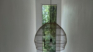 Ein Zimmer mit hohen Decken, einer Hängeleuchte, einem Fenster und einer Tür.