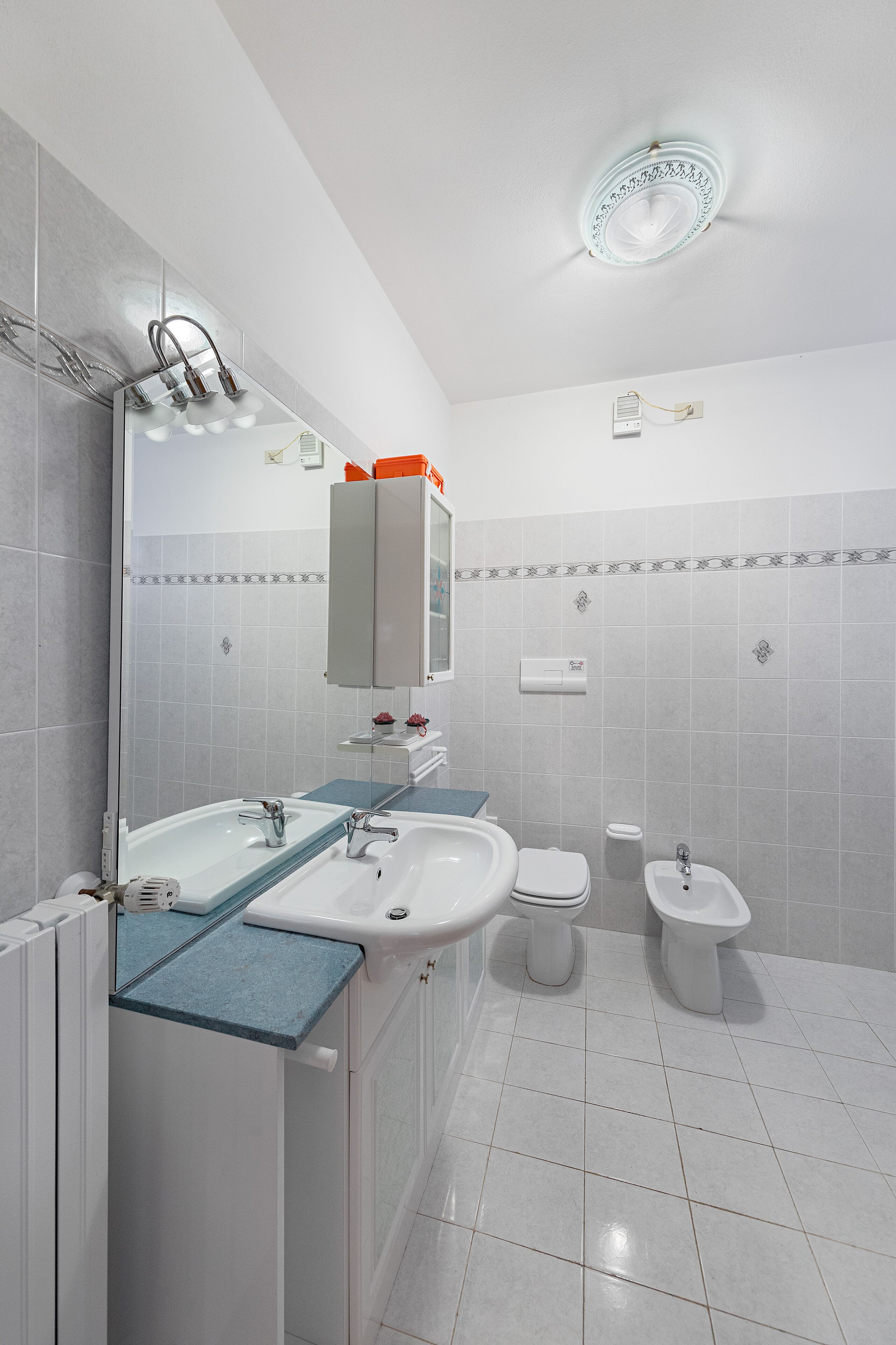 Un bagno moderno con uno specchio grande, due lavabi, un water e un bidet.