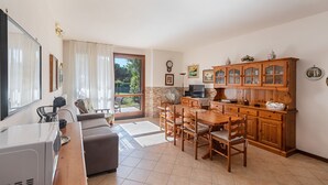 Un vaste espace de vie comprenant une table à manger, des meubles en bois et une grande fenêtre donnant sur un paysage verdoyant.