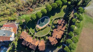 Vue aérienne d’un quartier résidentiel comprenant plusieurs maisons, une fontaine circulaire centrale et un chemin piétonnier aménagé.
