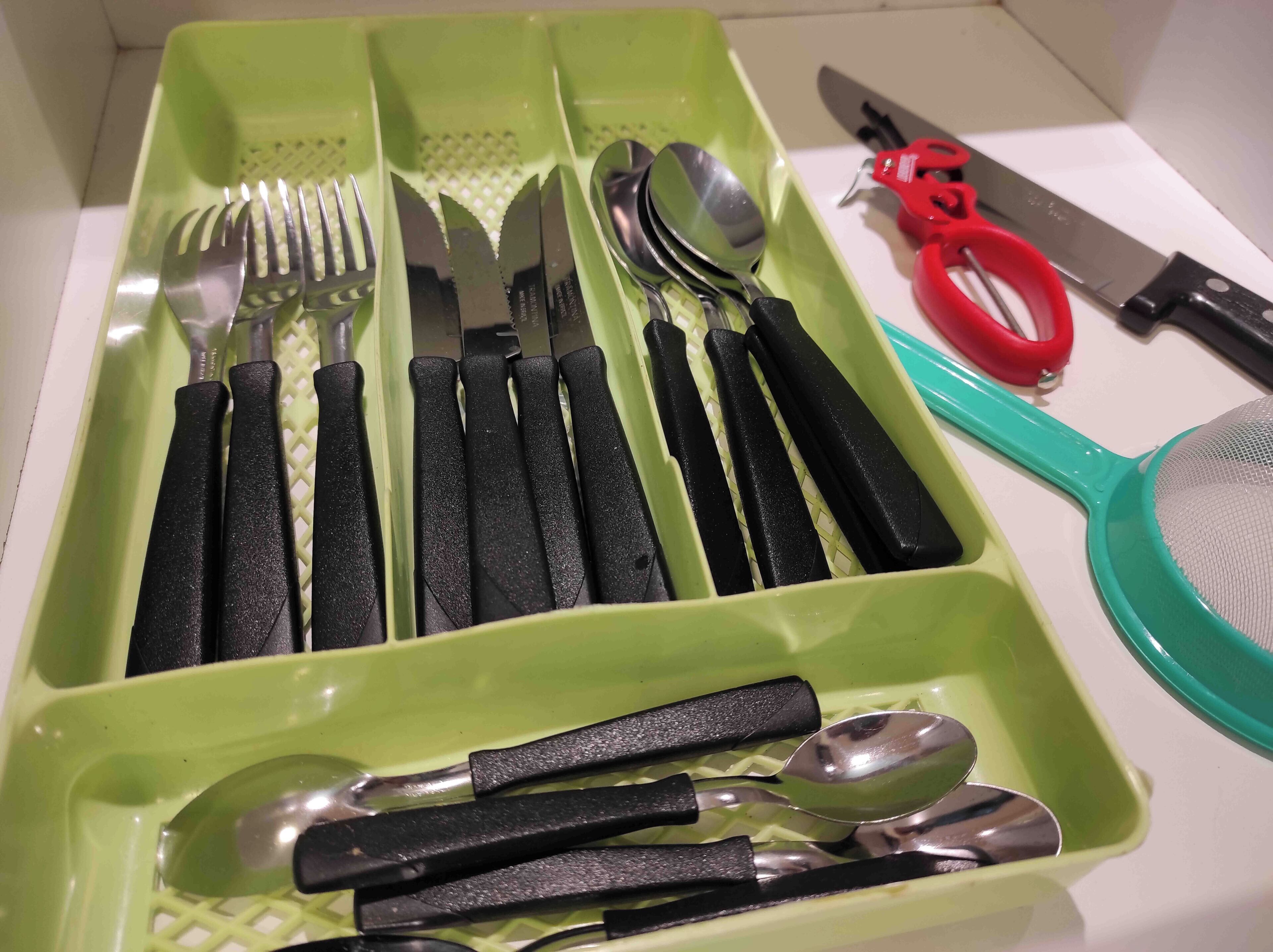 Ein grüner Besteckhalter mit verschiedenen Küchenutensilien wie Gabeln, Messern und Löffeln.