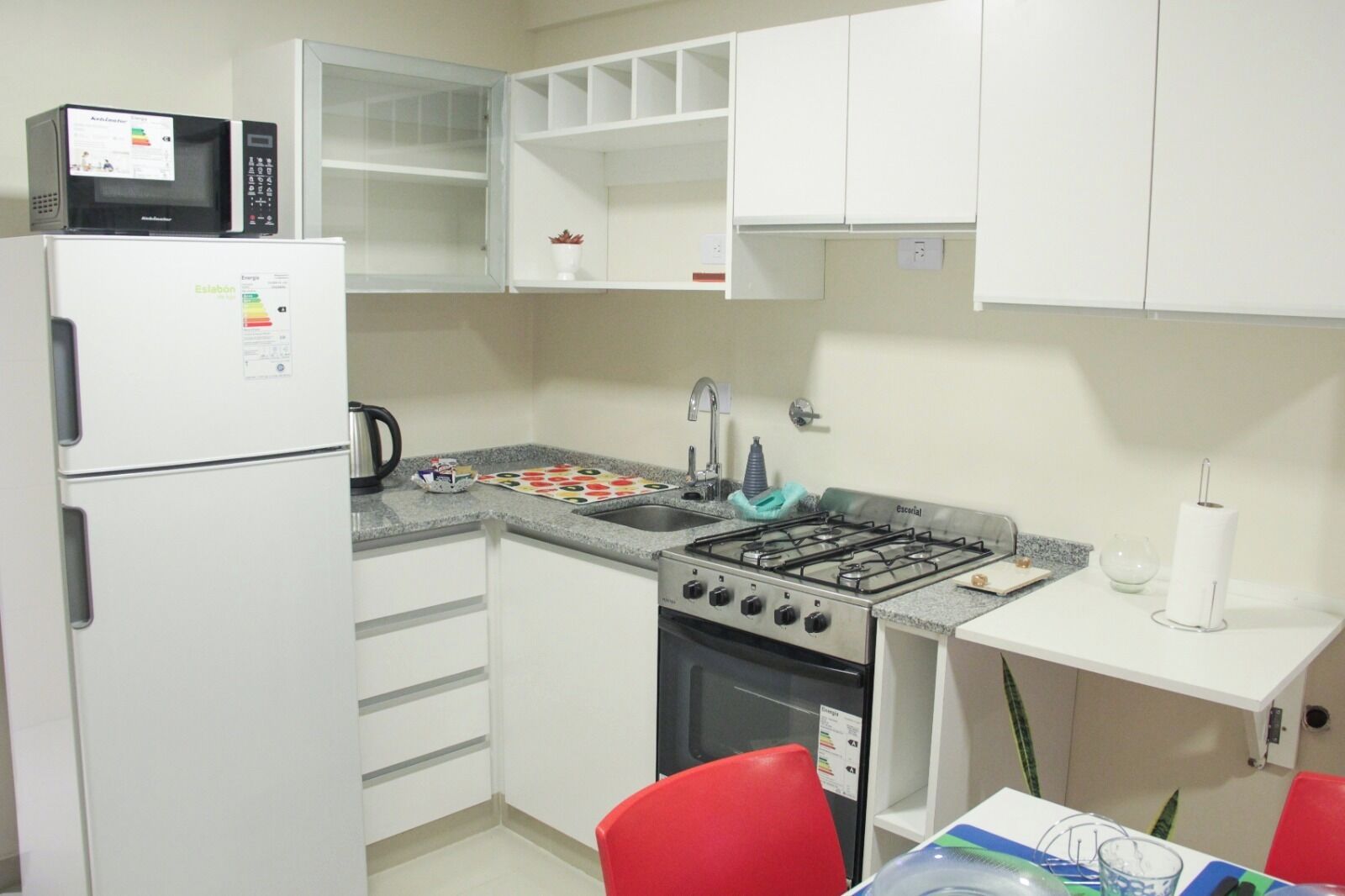 Una cocina compacta equipada con refrigerador, microondas, estufa a gas, horno y lavamanos.