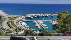 Un porto turistico con barche ormeggiate, circondato da vegetazione e con vista aperta sul mare.