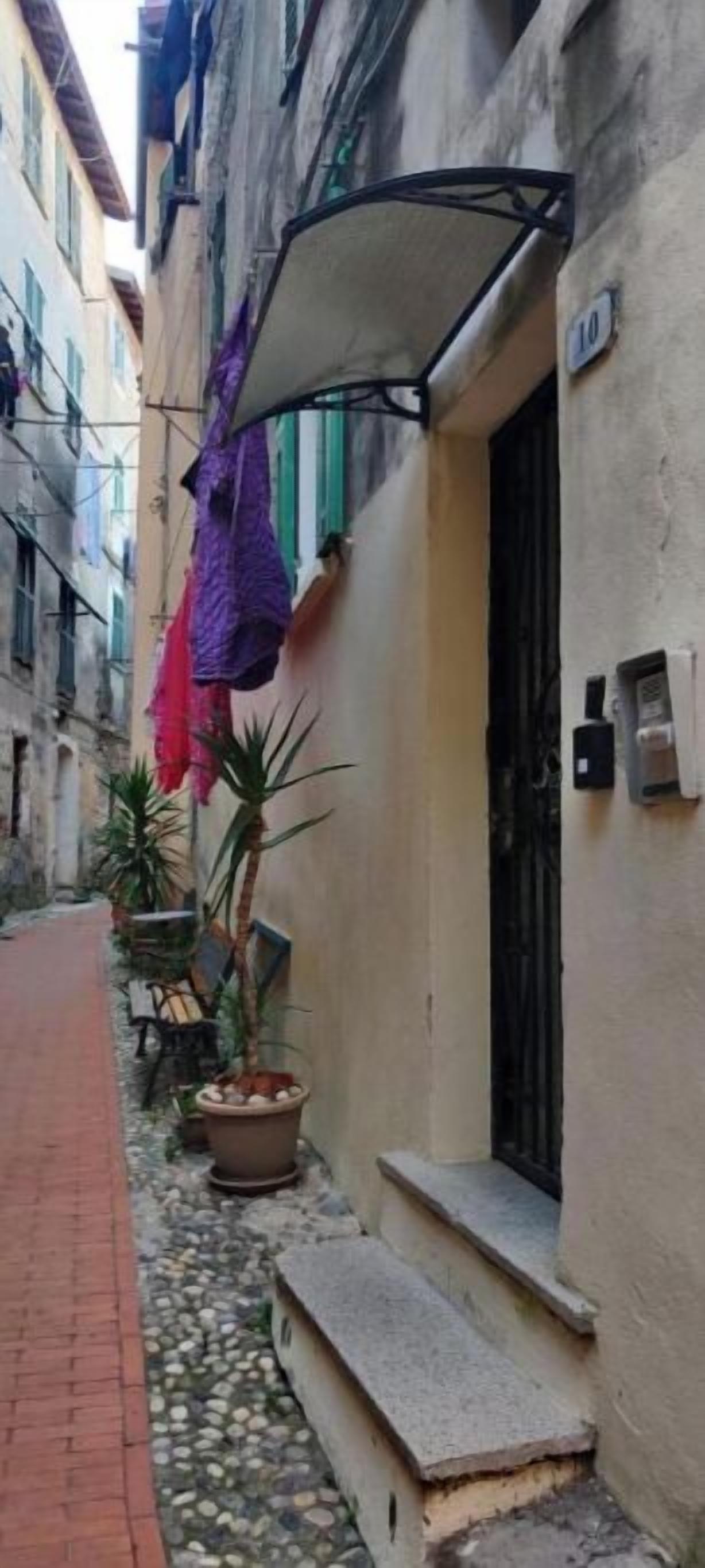 Un estrecho callejón con un edificio a la derecha. Un cartel en el edificio muestra el número 10.