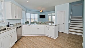 Une cuisine spacieuse avec des meubles blancs, un plan de travail en granit et un ventilateur de plafond.
