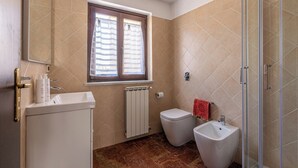 A bathroom with a toilet, bidet, sink, and a window with blinds. - Le terrazze nel cuore della Kalsa by Wonderful Italy (Palermo)