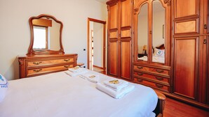 Habitación de hotel con un gran armario de madera, un espejo, una cama con toallas ordenadas y un aparador.