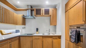 Une cuisine moderne avec des meubles en bois, une hotte de cuisine en acier inoxydable et un four encastré.